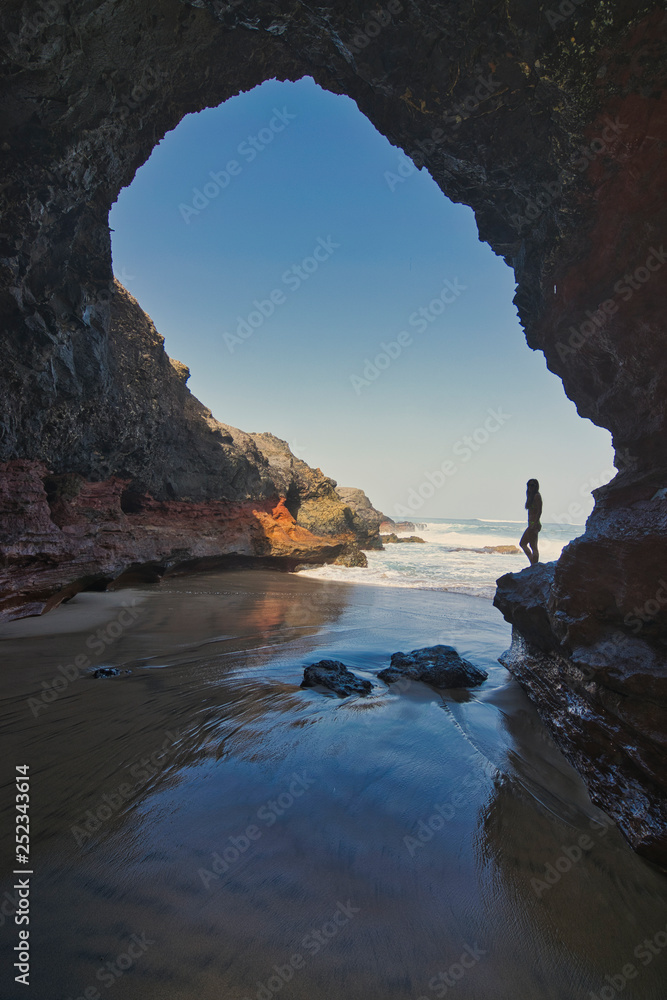 Mujer en una cueva con una play paradisíaca