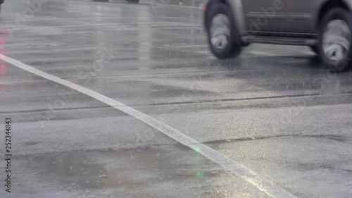 Cars drive across wet roads in a winter rain storm 