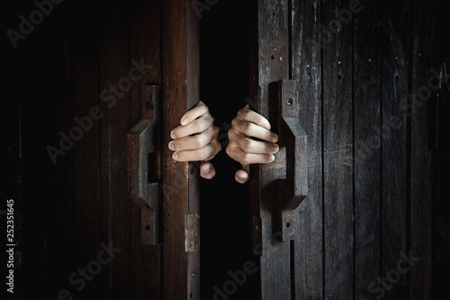 Hands open the wooden door from the inside of the dark room. photo