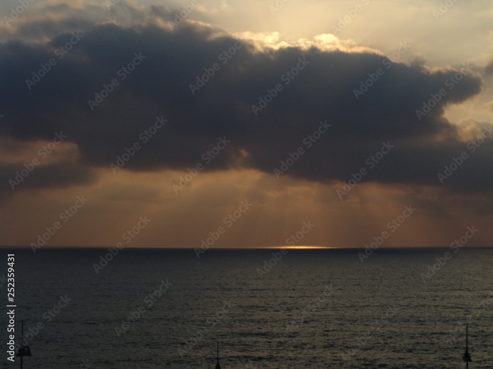 Cloudy sunset with light rays over the ocean