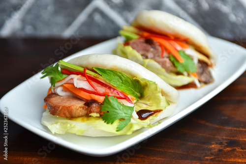 Fresh delicious pork steamed buns with BBQ sauce, coriander, mint, salad leaf and vegetables carrots, capsicum
