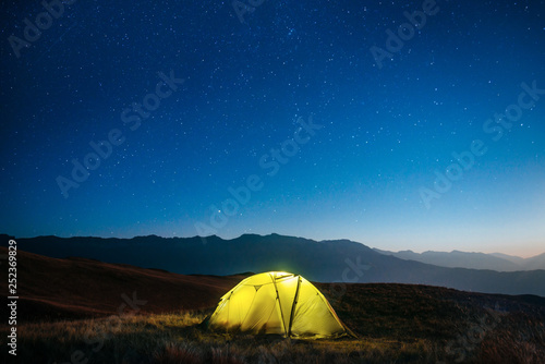 Yellow tent at night in the mountains