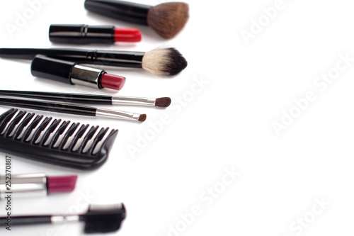 black makeup brushes and lipsticks on white background