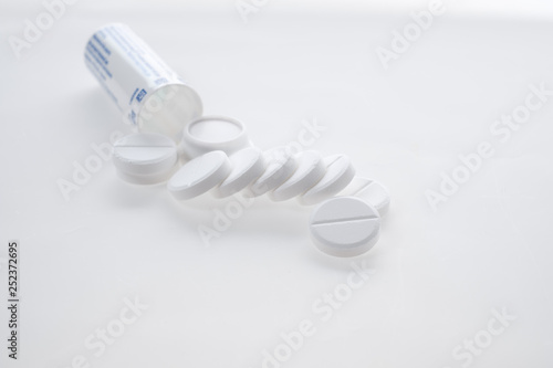Antipyretic tablets, painkillers scattered on the table on a white background