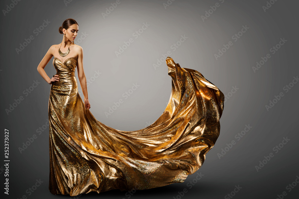 Woman Gold Dress, Fashion Model in Long Waving Fluttering Gown, Young Girl Beauty Studio Portrait - obrazy, fototapety, plakaty 