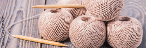 Balls of yarn and knitting needles for knitting on a wooden background.