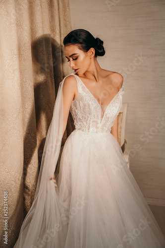 beautiful sensual bride with dark hair in luxurious wedding dress and accessories
