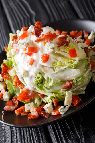 American Wedge Salad with iceberg lettuce, blue cheese dressing, bacon, and fresh tomatoes closeup on a plate on the table. horizontal 