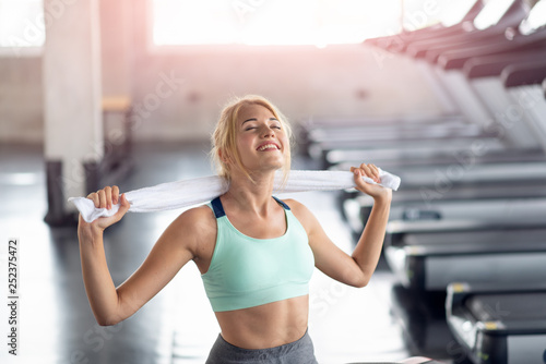 Happy woman staying with a towel after workout in the gym, Fitness and healthy lifestyle concept