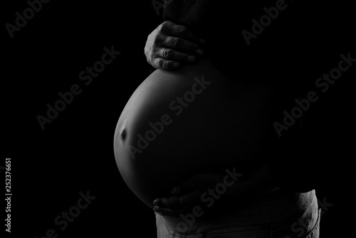 close-up of pregnant belly on a black background