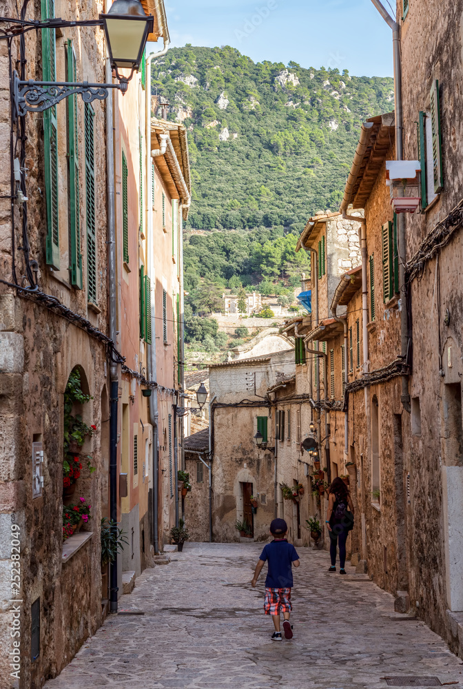Tourists walking in a narrow street in the old Valldemossa village - Mallorca, Spain