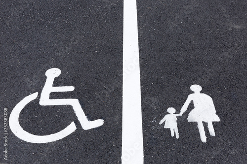 Handicap and Mother with child parking signs on asphalt.