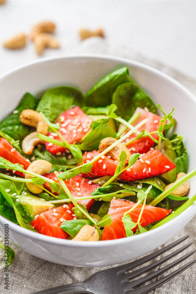 Summer strawberry avocado salad with cashews in a white bowl. Summer strawberry avocado salad with cashews in a white bowl.