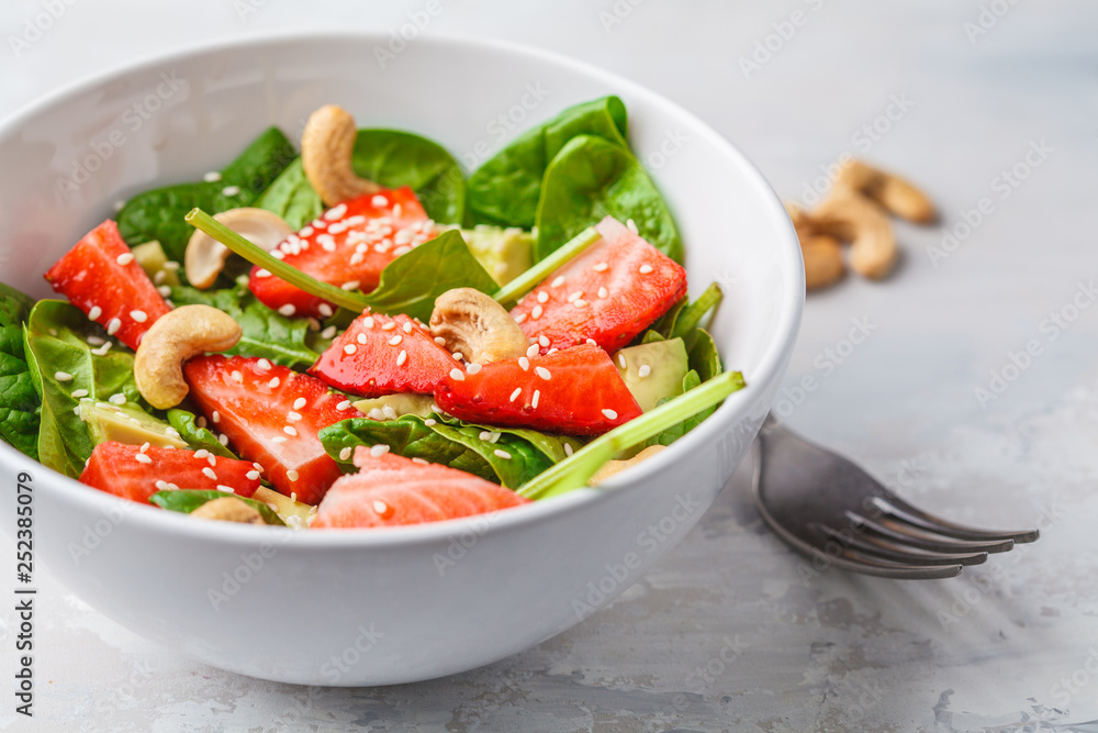 Summer strawberry avocado salad with cashews in a white bowl. Summer strawberry avocado salad with cashews in a white bowl.