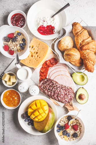 Continental breakfast table with croissants, jam, ham, cheese, butter, granola and fruit.