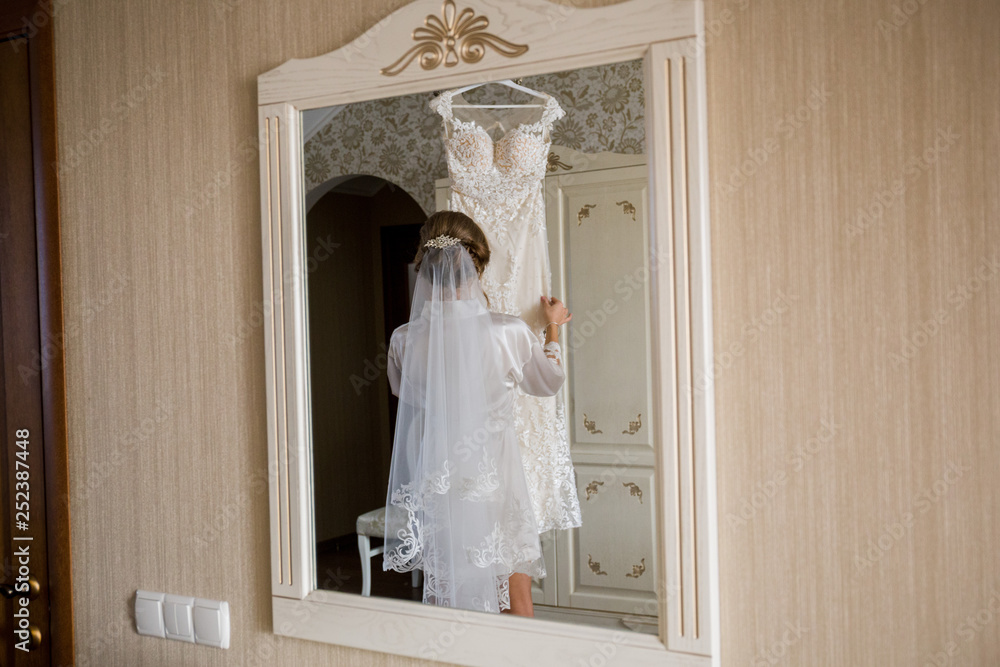 bride in bathrobe holding wedding dress in hands bride in bathrobe holding wedding dress in hands
