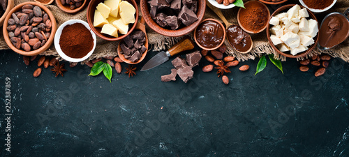 Cocoa beans, chocolate, cocoa butter and cocoa powder on a black background. Top view. Free copy space. photo