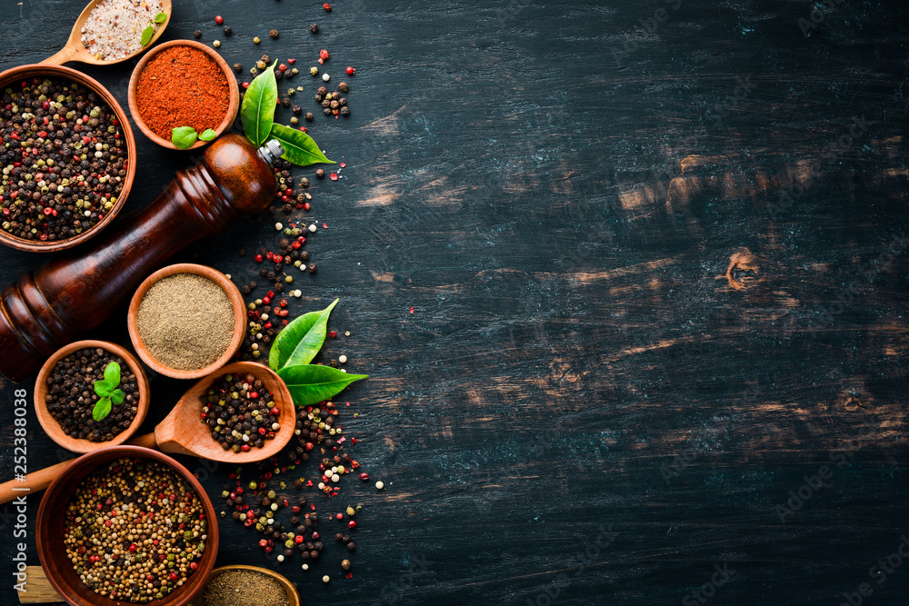 A set of peppers. Black pepper, colored pepper, ground pepper, dried chili pepper. Top view. On a black background. free space for your text. A set of peppers. Black pepper, colored pepper, ground pepper, dried chili pepper. Top view. On a black background. free space for your text.
