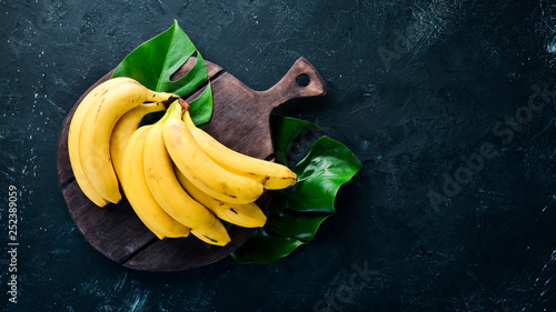 Fresh yellow bananas on a black stone table. Top view. Free copy space.