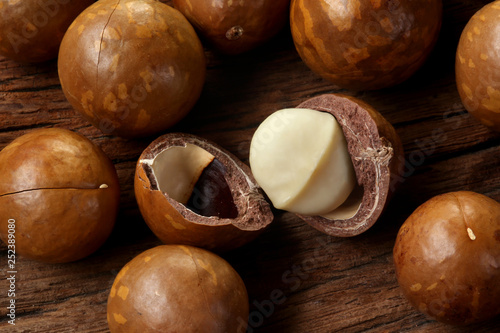 Roasted macadamias on wooden table, selective focus and toned image. Healthy food concept, free space for text.