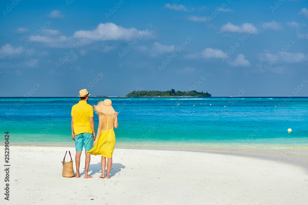 Couple in yellow on tropical beach at Maldives