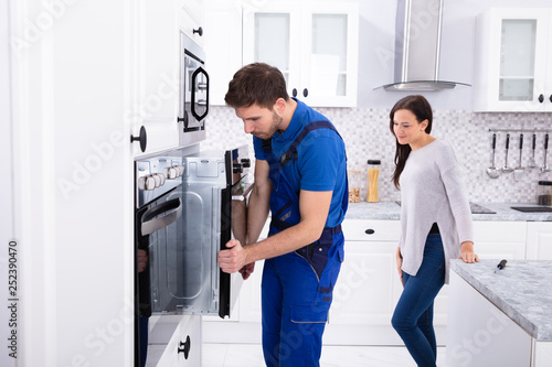 Young Serviceman Installing Oven In Kitchen