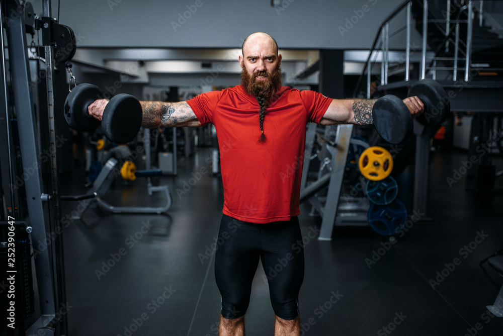 Weightlifter doing exercise with dumbbells in gym Weightlifter doing exercise with dumbbells in gym