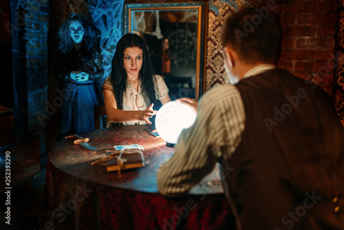 Couple on spiritual seance, witch on background