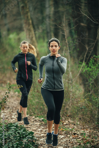 Two young beautiful woman exercise in the forest