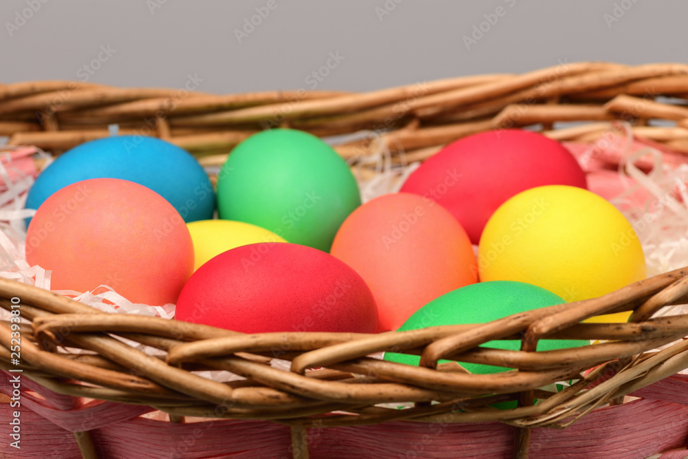 .Easter eggs are colorful in a wicker basket on a gray background. happy Easter. Horizontal photography. .Easter eggs are colorful in a wicker basket on a gray background. happy Easter. Horizontal photography.