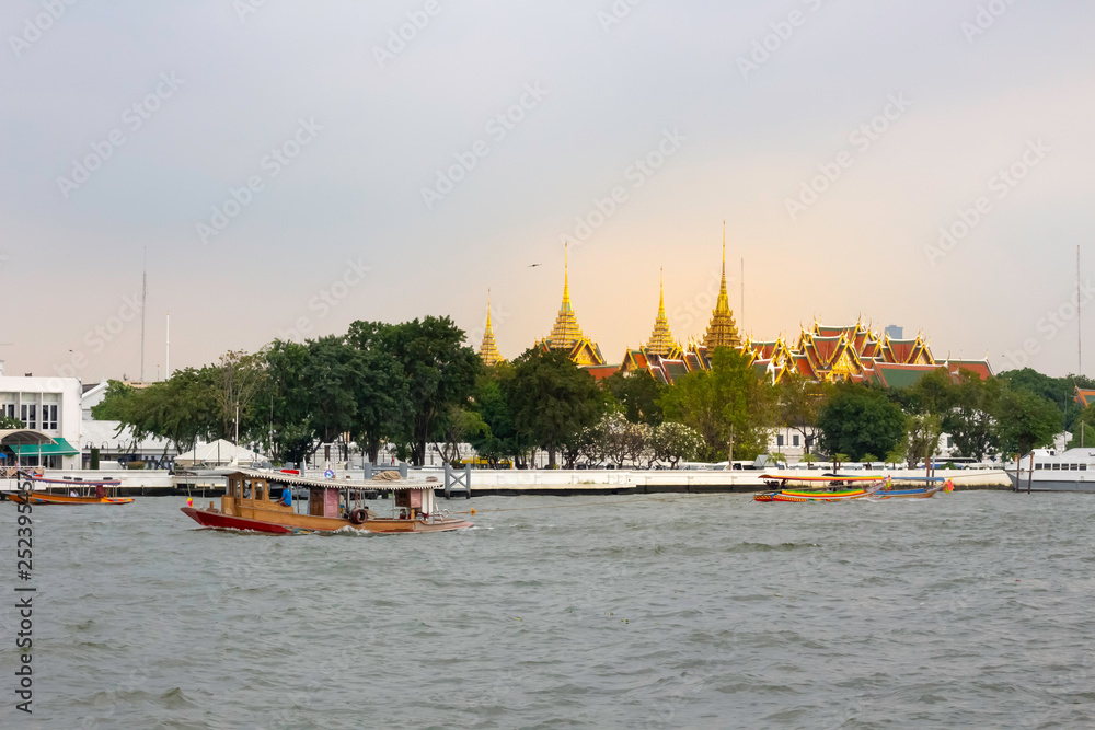 Passenger boats sail in the Chao Phraya River, passing in front of Wat Phra Kaew or Wat Phra Si Rattana Satsadaram Passenger boats sail in the Chao Phraya River, passing in front of Wat Phra Kaew or Wat Phra Si Rattana Satsadaram