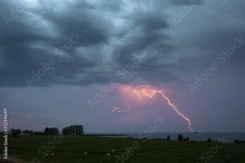 Dramatic sky with a spectacular lightning bolt striking in the water of the North Sea. 