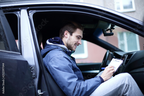 man signs a document while sitting in the car