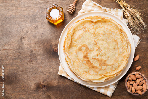 Crepes, thin pancakes with honey and nuts on a white plate . Wooden background . photo