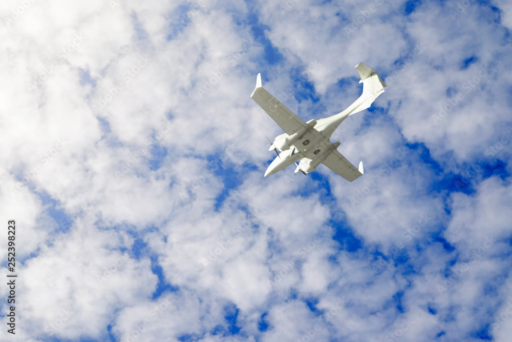 Obraz premium a small private white plane with screws flies on the background blue sky with clouds