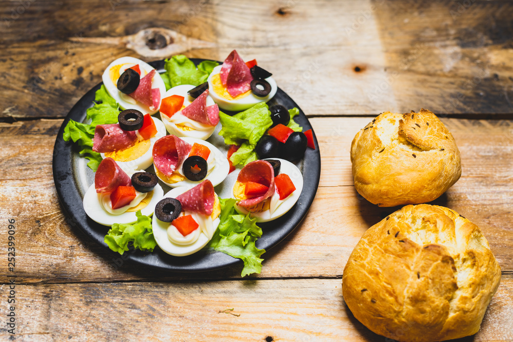 a plate of hard-boiled eggs, with the addition of mayonnaise, green leaves of lettuce, black olives and pieces of salami a plate of hard-boiled eggs, with the addition of mayonnaise, green leaves of lettuce, black olives and pieces of salami