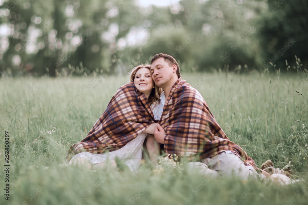 happy, married couple sitting together under a warm blanket on the lawn happy, married couple sitting together under a warm blanket on the lawn