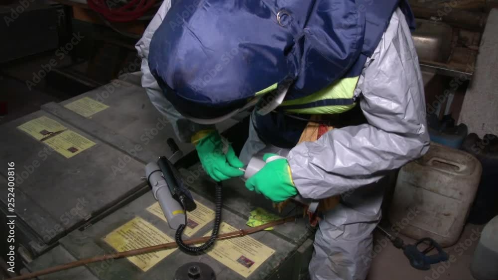 Man in hazmat outfit taking things for laboratory in abandoned factory. Indoors. CloseUp Man in hazmat outfit taking things for laboratory in abandoned factory. Indoors. CloseUp