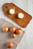 Unpeeled raw yellow onions on a white wooden table, top view. Flat lay, flat lay, from above.