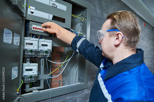 Photos Electrician works in fuse box. Switching of circuit breaker