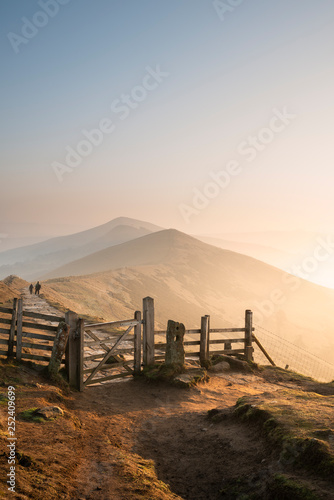 Stunning Winter sunrise landscape image of The Great Ridge in the Peak District in England with a cloud inversion and mist in the Hope Valley with a lovely orange glow