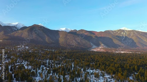 Wallpaper Mural Aerial view of the slide on the panorama of snow-capped mountain peaks and on the roofs of resort ski resorts at dawn of the day in the early morning. Bright morning sun in winter. Floating mist  Torontodigital.ca