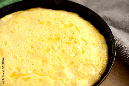 Porous omelet in a pan. Close-up. Omelette of chicken eggs and milk in a pan on the table. Freshly cooked omelette. The protein in the dish for breakfast.