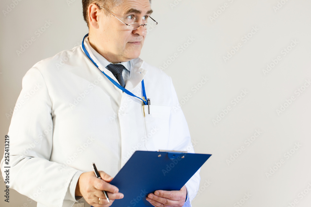 A doctor in a white coat looks into the distance and holds a folder and a pen A doctor in a white coat looks into the distance and holds a folder and a pen