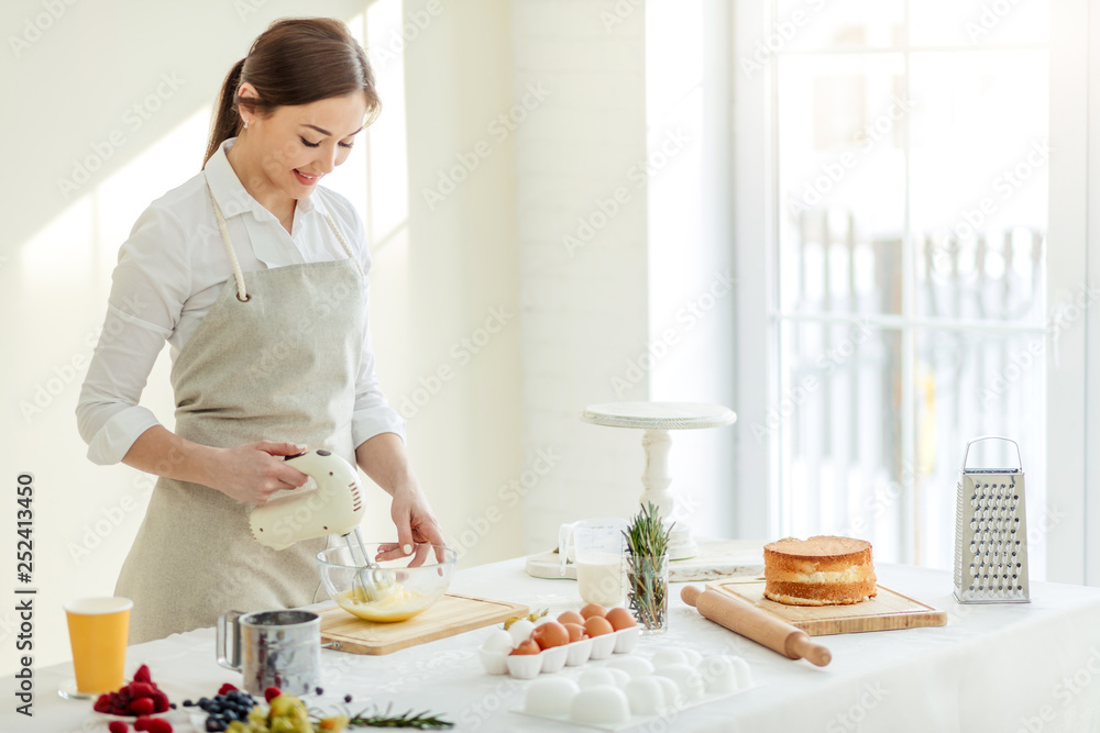 cheerful beautiful girl mixing eggs in the kitchen with modern interior. close up photo. copy space cheerful beautiful girl mixing eggs in the kitchen with modern interior. close up photo. copy space