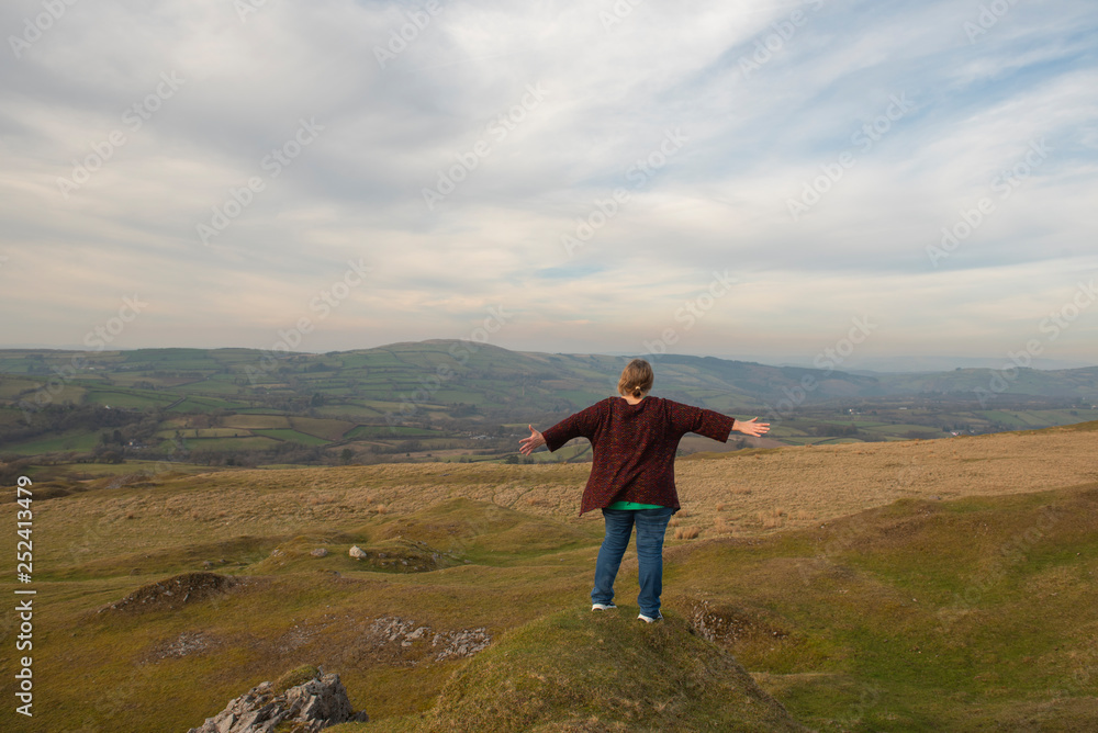 Obraz premium Mature woman with outstretched arms overlooking rural view