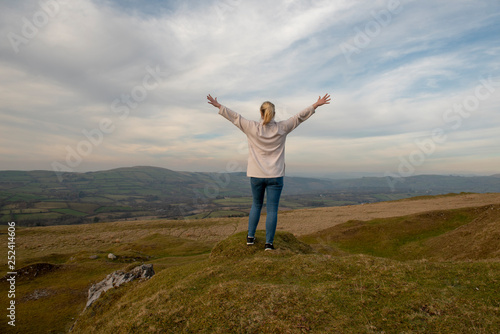 Young woman with outstretched arms overlooking rural view