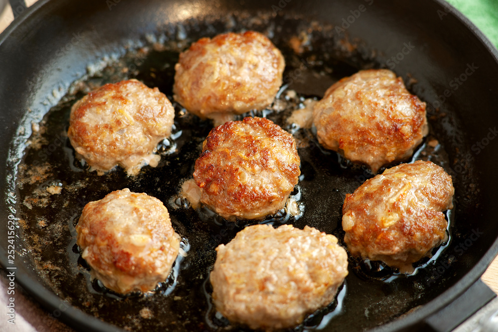 Cutlets are fried in a pan. Beef and pork cutlets are fried in a cast-iron pan. Meat dish in the cooking process. Meat patties in oil.