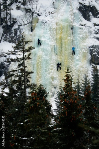 Three men climbing the icefall in winter