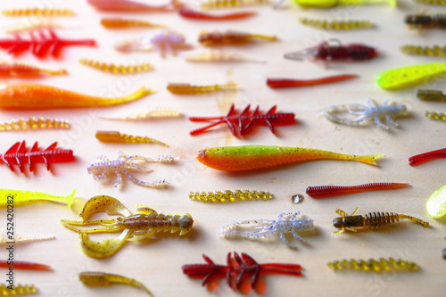 Colorful silicone fishing baits with plummets on wooden table. Various fish and worms and crayfish. Toned image and top view. Stock background, photo